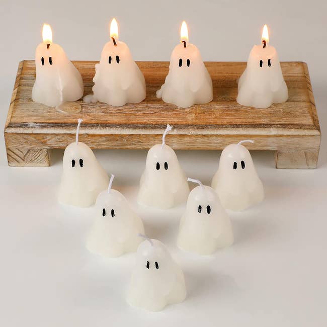 Ghost-shaped candles connected  a woody  tray, immoderate   lit and immoderate   unlit, arranged successful  a decorative buying  display