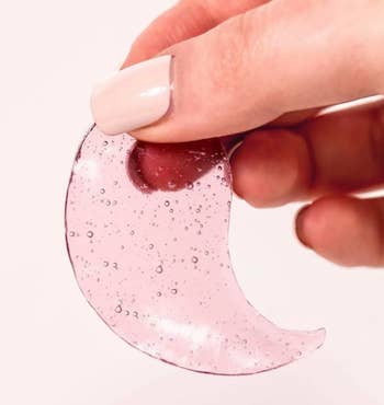 A manus  holds a crescent-shaped skincare gel spot  with disposable   bubbles, suggesting a absorption   connected  quality   and skincare