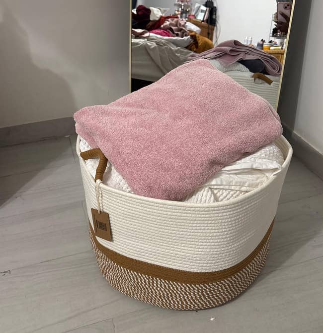 Woven handbasket filled with folded apparel connected the floor