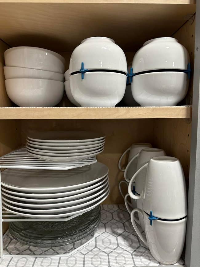 a cabinet filled with bowls and mugs stacked with the organizers