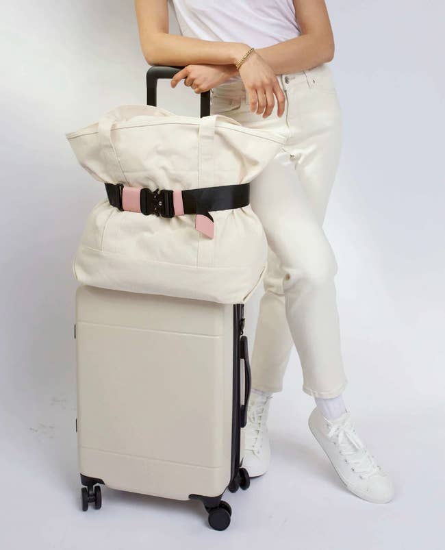 a model with a suitcase that has a bag on top being held on with the strap