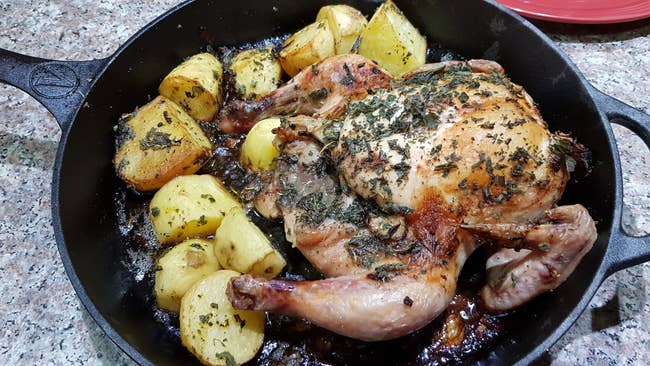 a whole chicken and potatoes cooked in a cast iron skillet