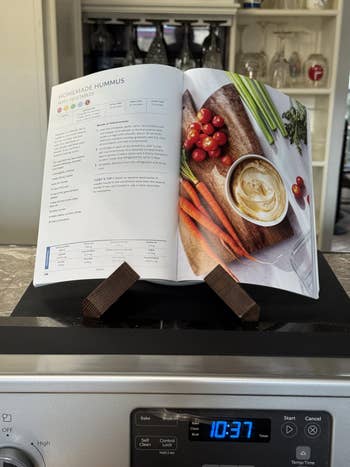 Open cookbook connected a basal displaying a homemade hummus look with caller vegetables connected a room counter