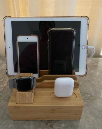 reviewer image of dock charging earbuds, a watch, two phones, and an ipad