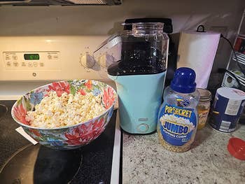 The popcorn machine on the kitchen counter with a bowl of popped popcorn and kernels