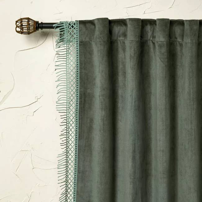 a dark green curtain hanging on a gold rod