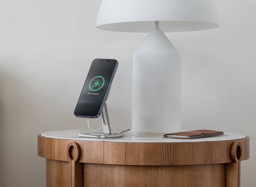 an iPhone charging on the magnetic MagSafe charger on a bedside table