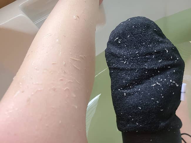 a reviewer' removing dry skin from their legs with an exfoliating glove