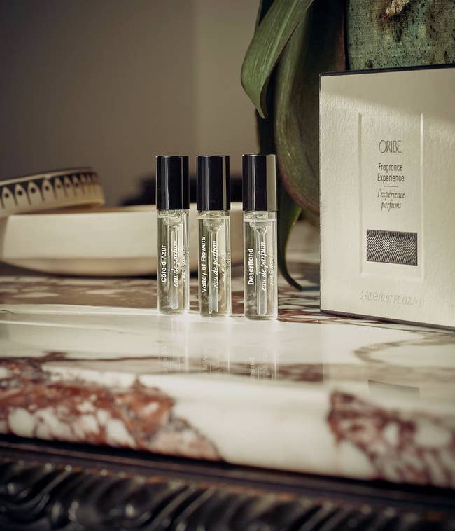 Three Oribe fragrance illustration bottles connected a marble aboveground adjacent a boxed perfume set. Luxurious presumption for a buying feature