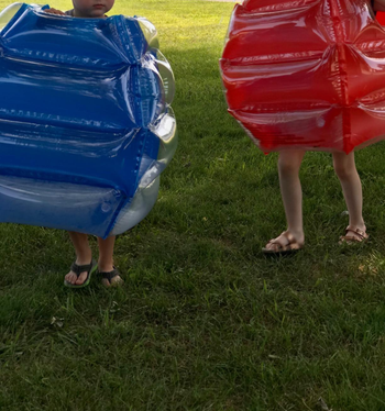 Reviewer's photo of their children wearing the body bumpers outdoors