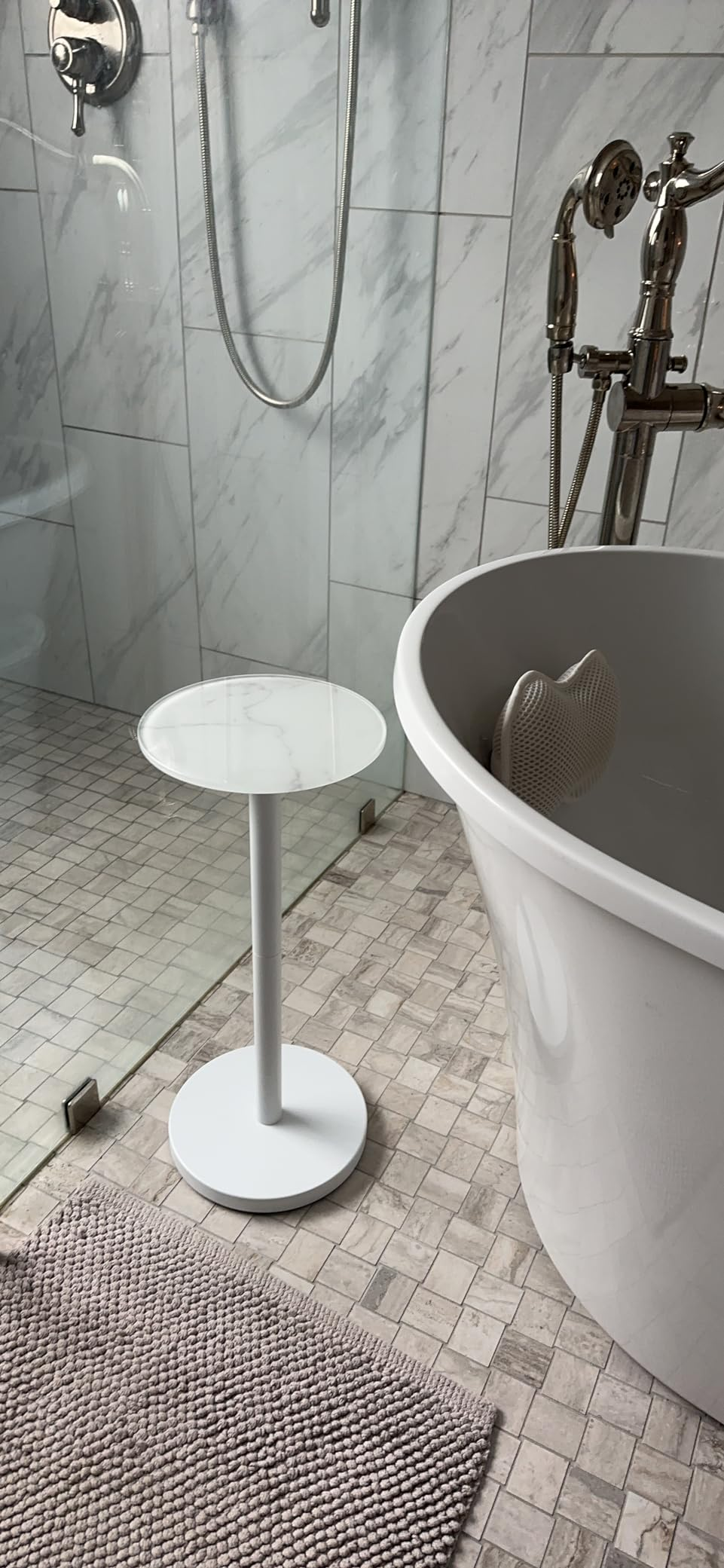 Bathroom with a walk-in solid  shower, a freestanding tub, and a tiny  circular  broadside  table. Marble and tiled surfaces make  a modern   look