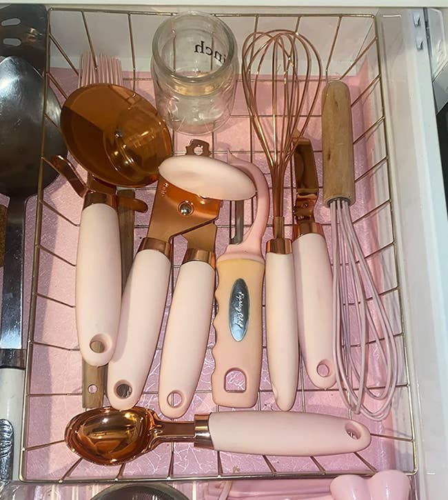 The gadgets in a drawer with copper heads and pale pink handles 