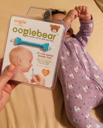 reviewer holding oogiebear in container in front of their baby