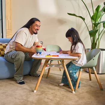 Adult and kid sitting astatine a tiny array playing