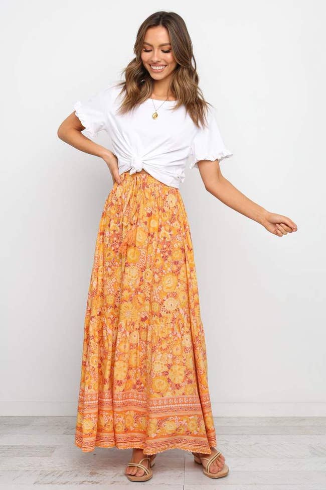 a model in a maxi skirt with an orange boho pattern on it