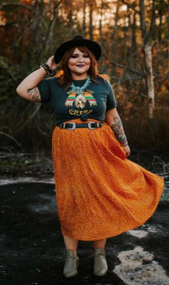 a reviewer wearing a T-shirt tucked into the printed midi skirt in orange 