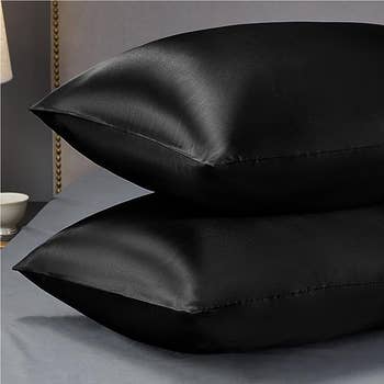 Two satin pillow cases in black stuffed with pillows