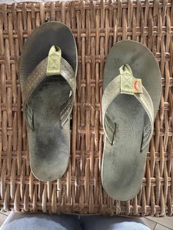 Worn flip-flops with textured soles and cloth  straps connected  a wicker surface, showcasing durability and comfortableness  for casual wear