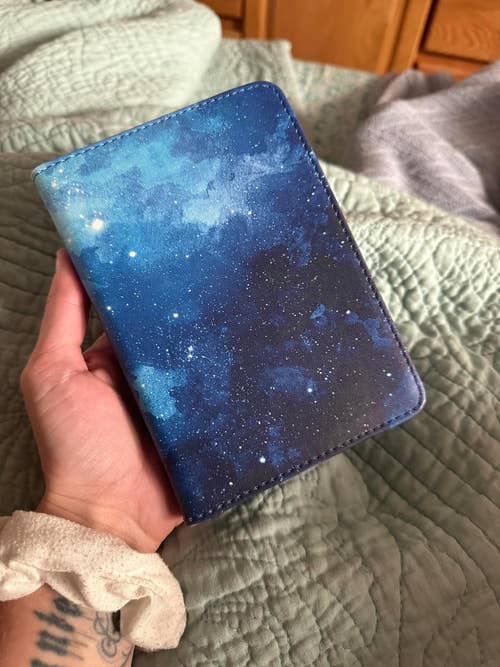reviewer holding their Kindle in the blue starry sky case