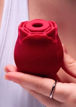 Person holds a silicone rose-shaped product, apt  a idiosyncratic   attraction   item, highlighting its compact and ergonomic design