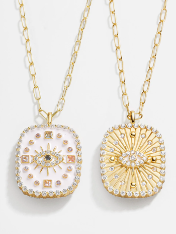 reversible evil eye pendant showing one side with pink enamel and multicolor crystals and the other side with gold and clear colored crystals