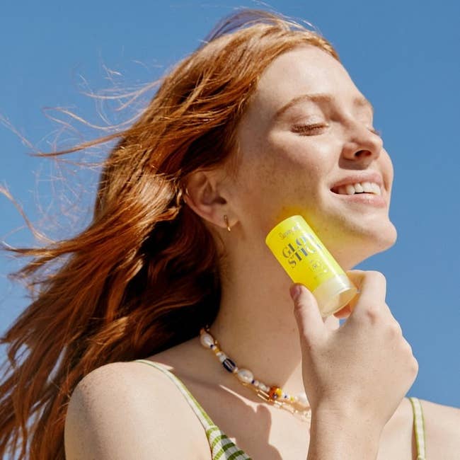 a model holding the bottle of supergoop dry oil sunscreen
