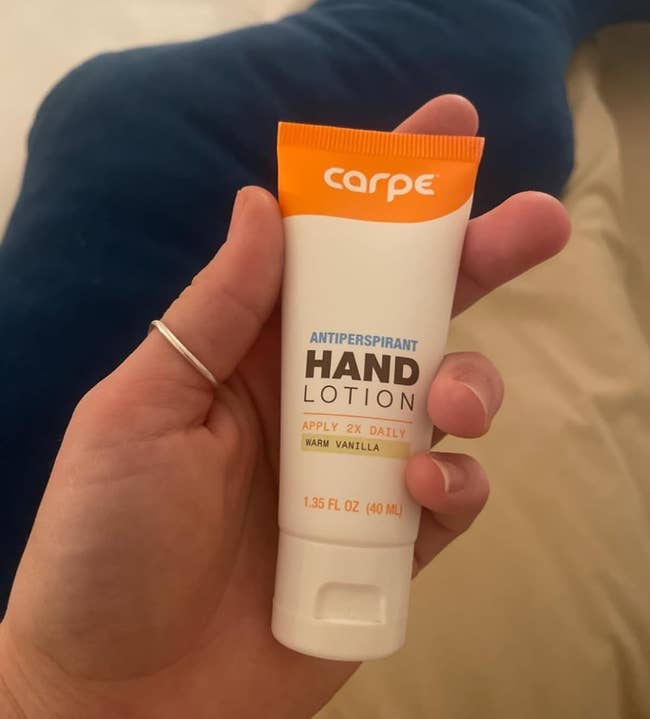 Person holding a tube of Carpe antiperspirant hand lotion