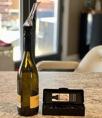 a reviewer photo of the wine aerator on top of a wine bottle
