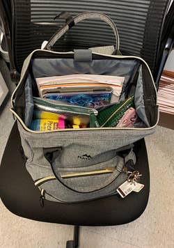 a reviewer photo of the main compartment of the bag open and filled with office supplies 
