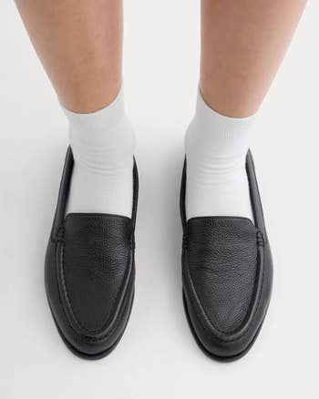 Black loafers worn with achromatic socks, viewed from above, showcasing a elemental and classical style