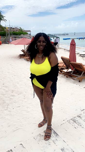 reviewer wearing ruched yellow swimsuit and black cover-up
