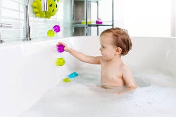 child sticking the toy to the side of a bathtub