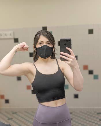 reviewer gym mirror selfie flexing, wearing black mask and black cropped tank top