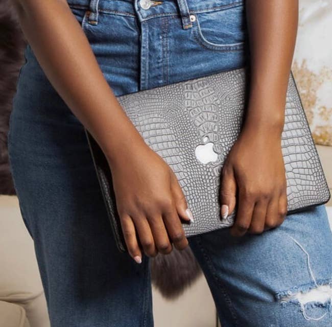 a model holding the black laptop case in crocodile print 