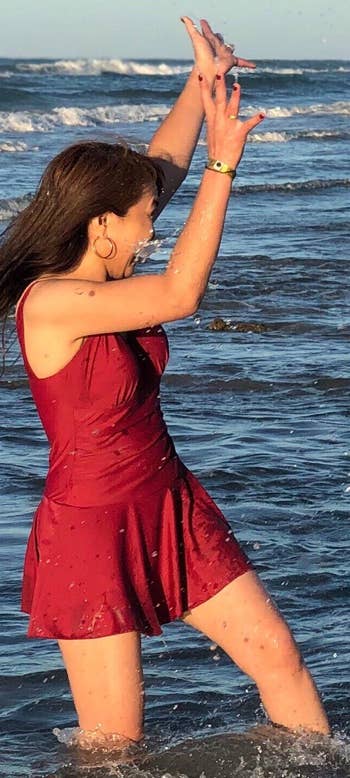 reviewer in the water wearing the red swimdress