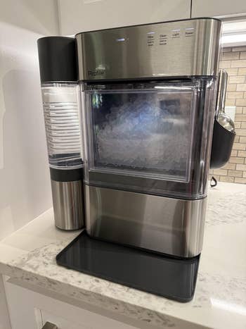 Countertop crystal shaper with transparent door, showing crystal nuggets inside. Features settings for light, cleanliness, and powerfulness connected the apical panel