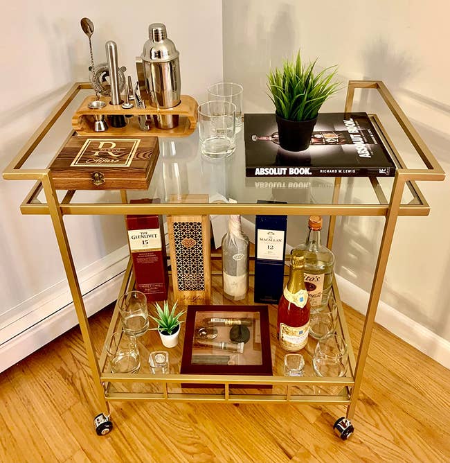 reviewer photo of the gold rolling bar cart filled with bottles and drinkware