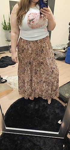 Person successful  a floral-patterned agelong  skirt and graphic vessel  apical  taking a reflector  selfie, lasting  connected  a rug successful  a country   with plants and casual items