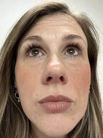 reviewer with agelong  eyelashes and airy  lipstick looking upward; has airy  earrings visible