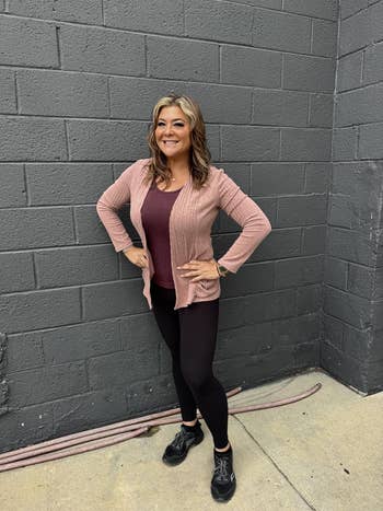 Person successful a casual outfit with a textured cardigan, lasting confidently outdoors against a ceramic wall