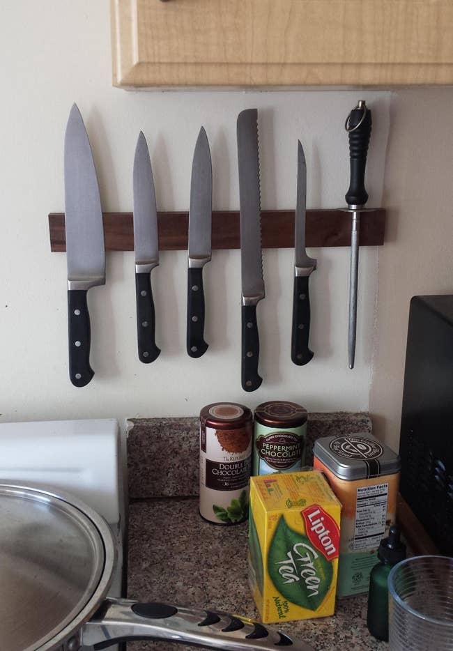 reviewer image of several knives hanging from the wall-mounted magnetic knife strip