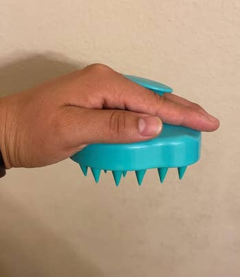 Side view of reviewer holding scalp massager showing the bristles and how easy it is to grip