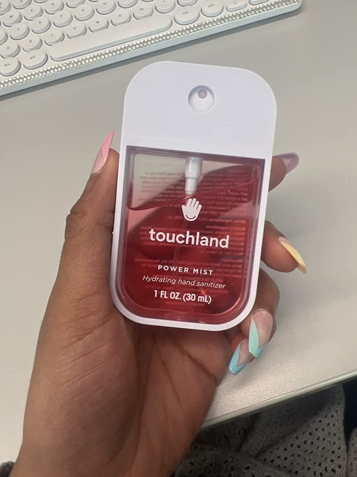 a reviewer holding the palm size spray bottle of sanitizer