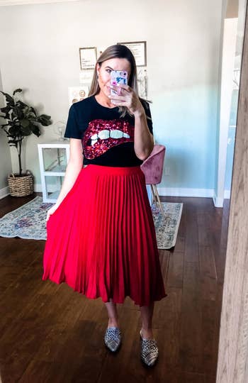 another reviewer wearing the pleated skirt in red with a black top and flats