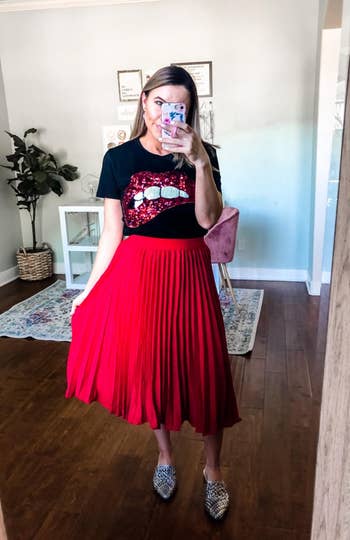 another reviewer wearing the pleated skirt in red with a black top and flats