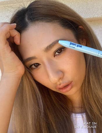 Model with natural makeup holding pen pa;
