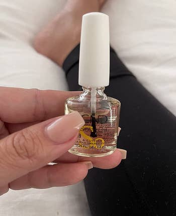reviewer holding a bottle of the cuticle oil