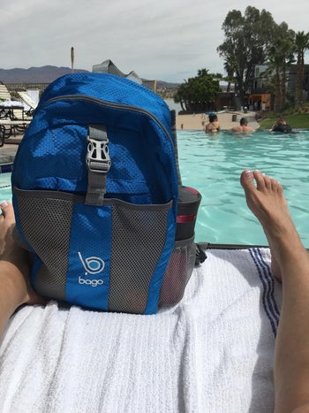 reviewer photo of a blue backpack with a pool in the background