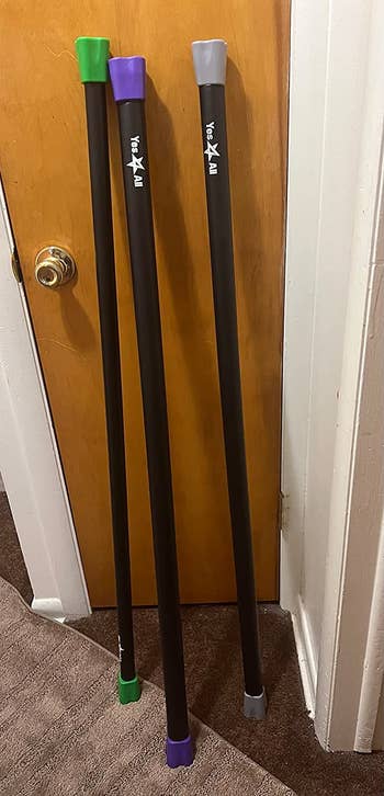 Reviewer's three weighted workout bars leaning against a door