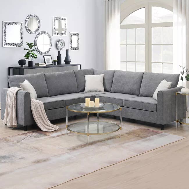 the gray sectional couch with three white pillows on top